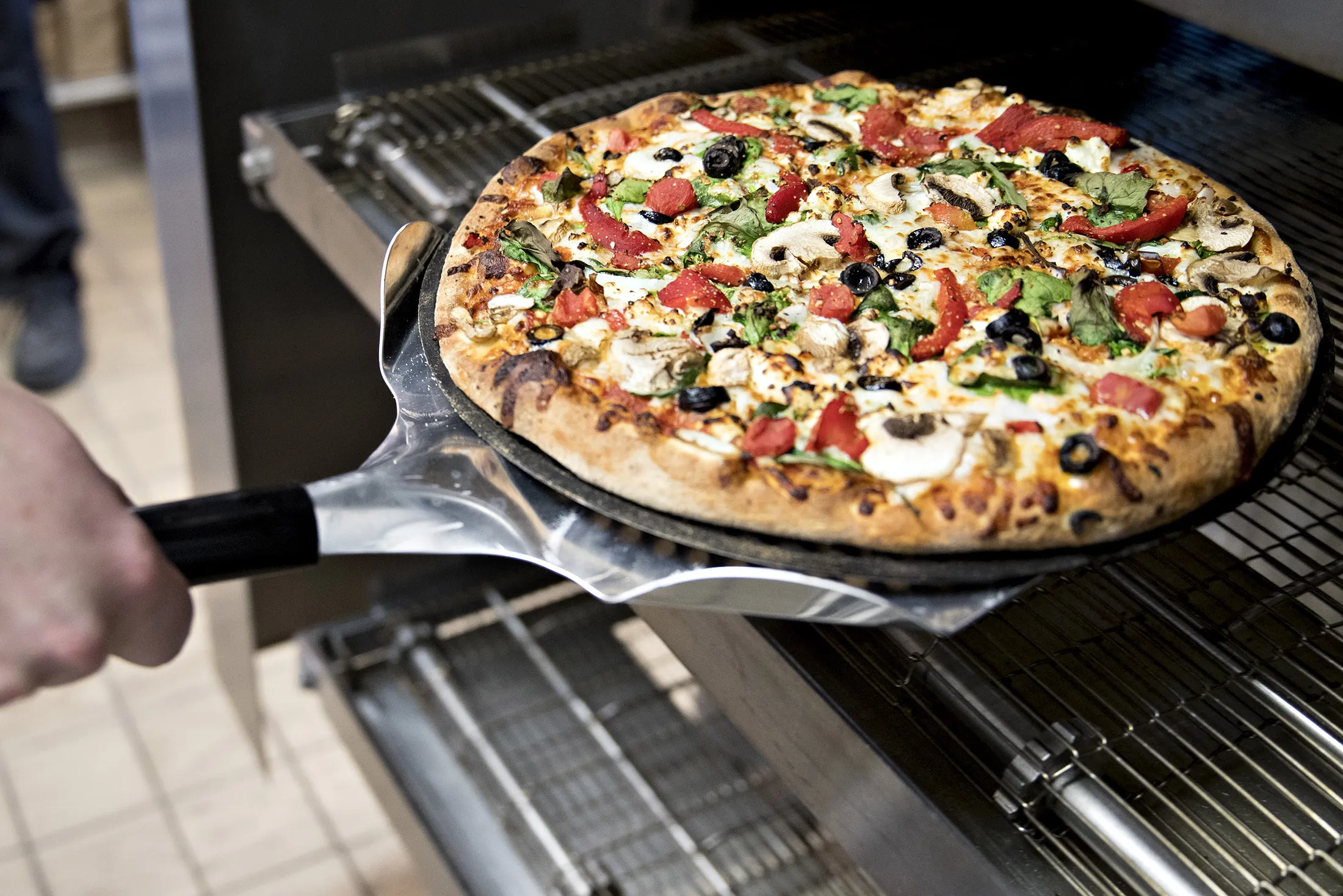 An employee removes a pizza from an oven at a Domino's Pizza Inc. restaurant.