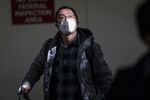 A traveler arriving on a flight from Beijing wears a disposable face mask at San Francisco International Airport in San Francisco, California, U.S.