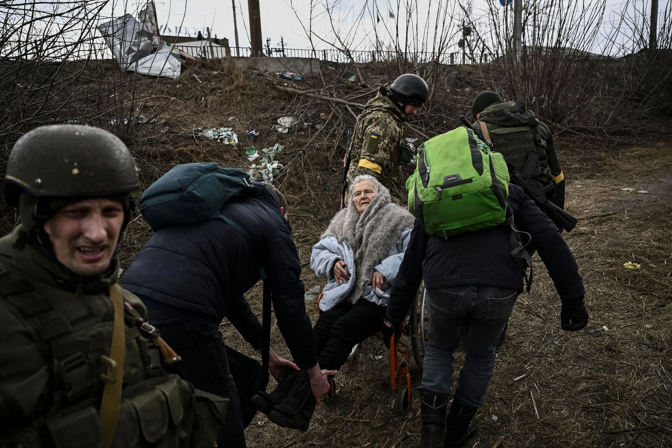 People help an elderly woman in a wheelchair as they flee the city of Irpin&nbsp;on March 7.