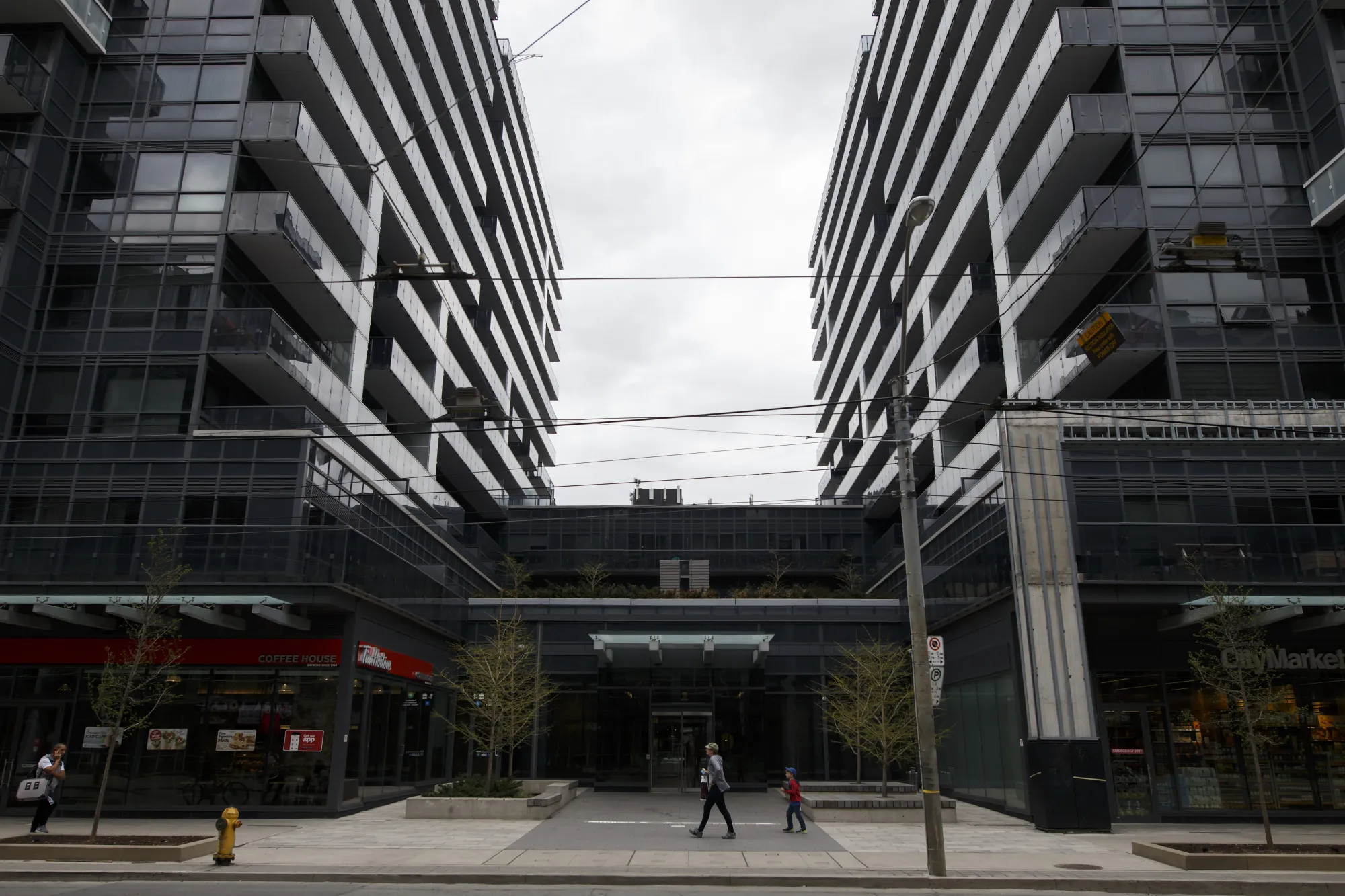 Pedestrians walk past condominium buildings in downtown Toronto.