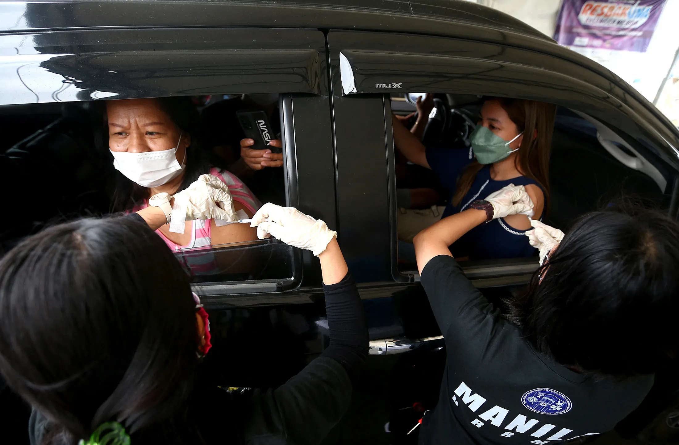 People receive Pfizer-BioNtech booster shots at a drive-thru Covid-19 vaccination site in Manila on Jan. 13.