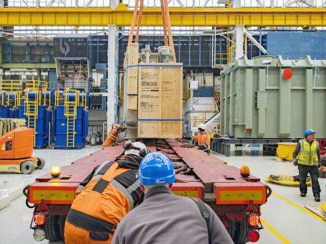 A completed power transformer, which is very dense and heavy,  is loaded on to a lorry by crane at the Vernova factory.