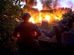Soldiers&nbsp;take cover in front of a burning building on Monday&nbsp;in Druzhkivka, Ukraine.&nbsp;