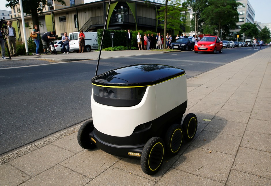 A Starship Technologies commercial delivery robot navigates a sidewalk.