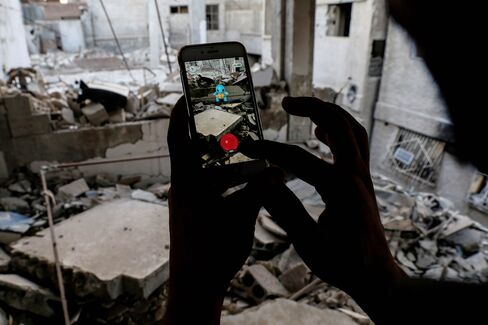 A Syrian gamer uses the Pokemon Go application on his mobile to catch a Pokemon amidst the rubble in the besieged rebel-controlled town of Douma, Syria.