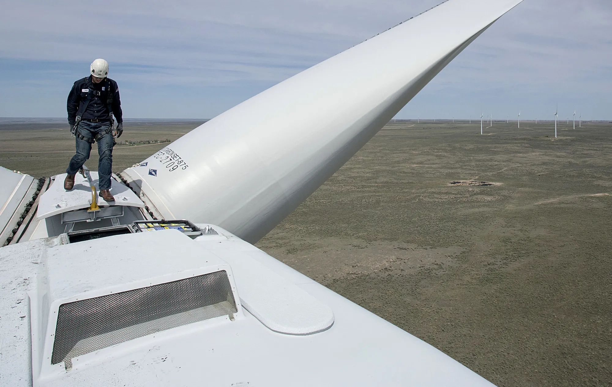 A renewable energy technician walks on a wind turbine in Fleming, Colorado.
