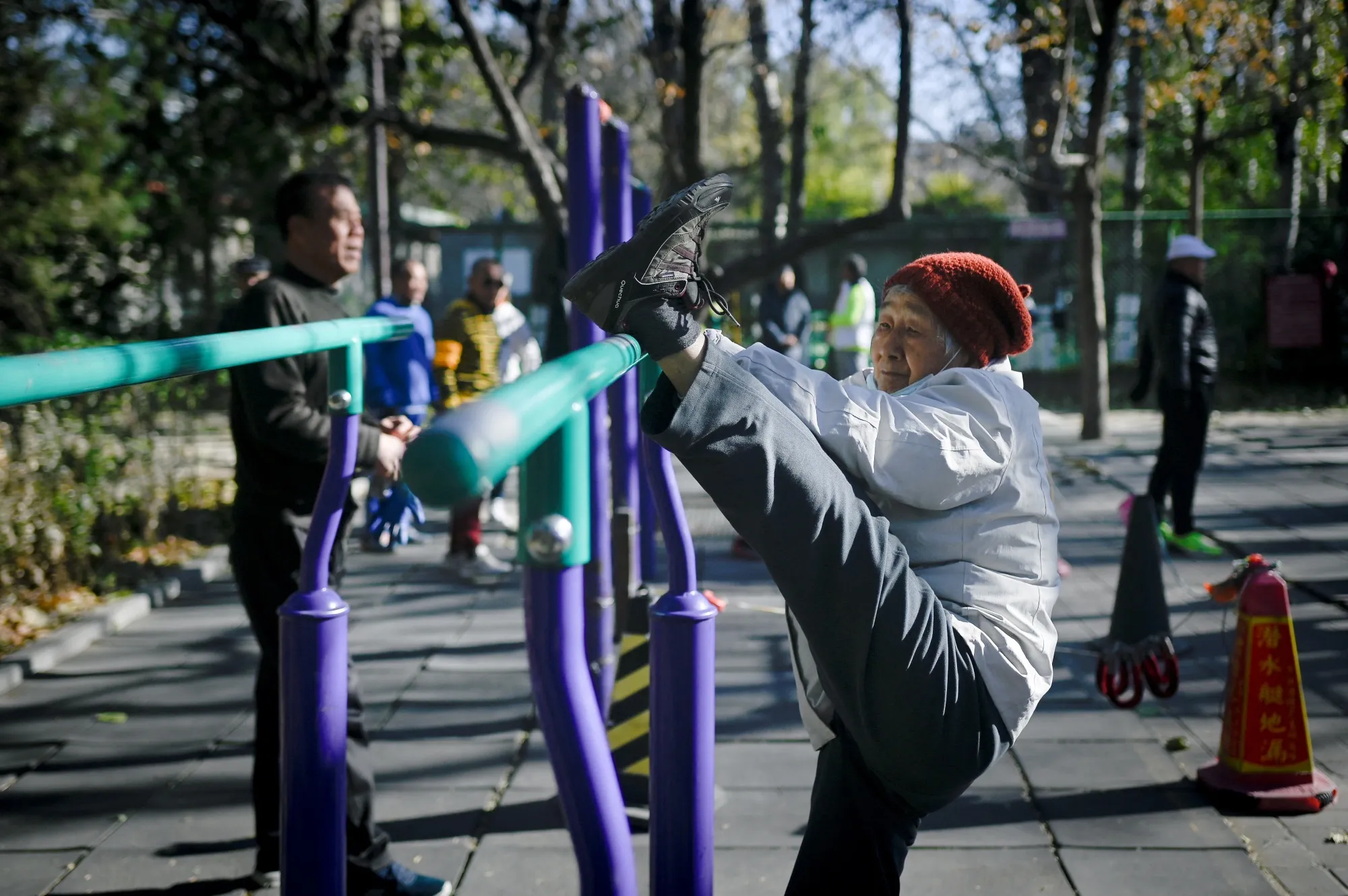 An elderly woman exercises at a park in Beijing.