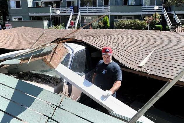 A man attempts to disentangle his daughter's car after the car port it was parked in collapsed on top of it as a result in downtown Napa, Calif., after an earthquake struck the area