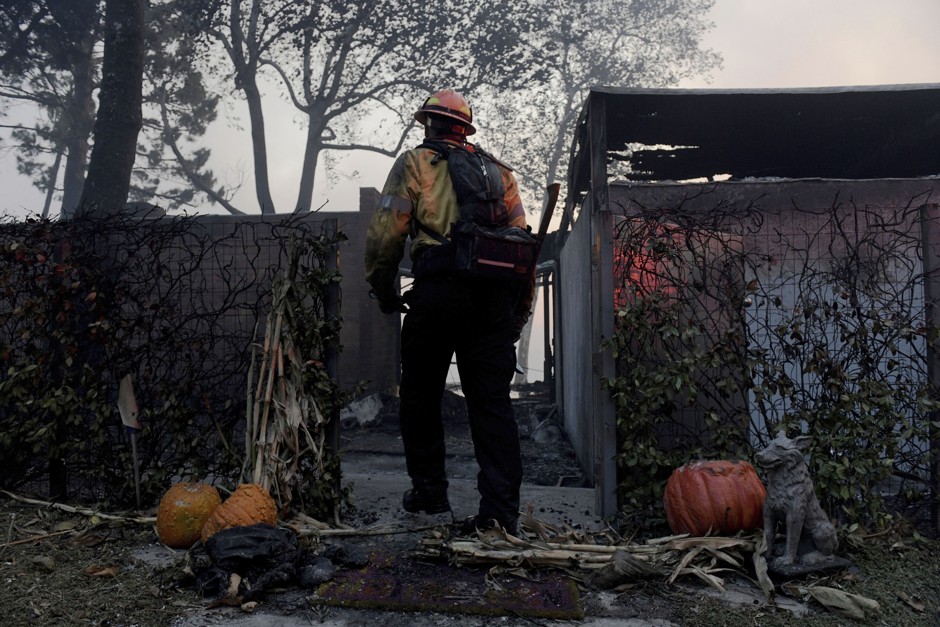 A firefighter works to clear a house destroyed by a wildfire in Los Angeles.