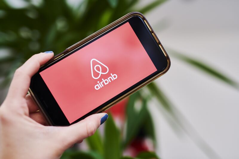 Image: a hand holding a phone with the airbnb localized mobile app.