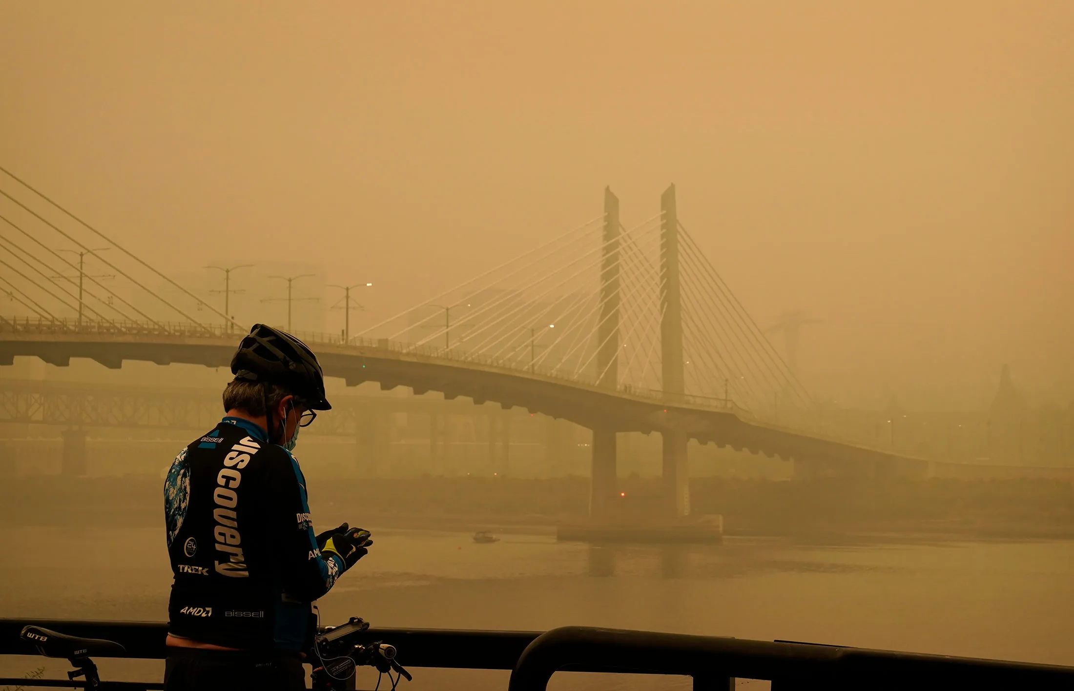 A cyclist&nbsp;stops along the Willamette River as smoke from wildfires fills the air, in Portland, on Sept. 12.