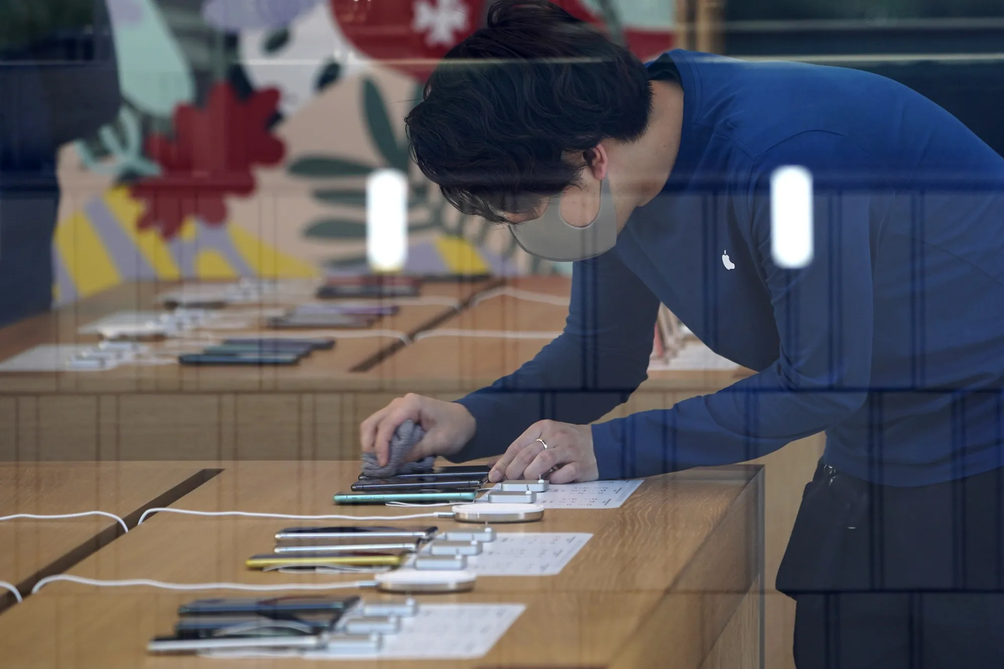 An employee cleans the screen of an Apple Inc. iPhone inside the company's store, temporarily closed due to the coronavirus, in Tokyo.