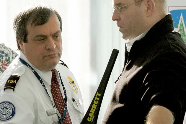 A U.S. Transportation Security Administration employee passes a metal-detecting wand over a traveler's chest at O'Hare International Airport