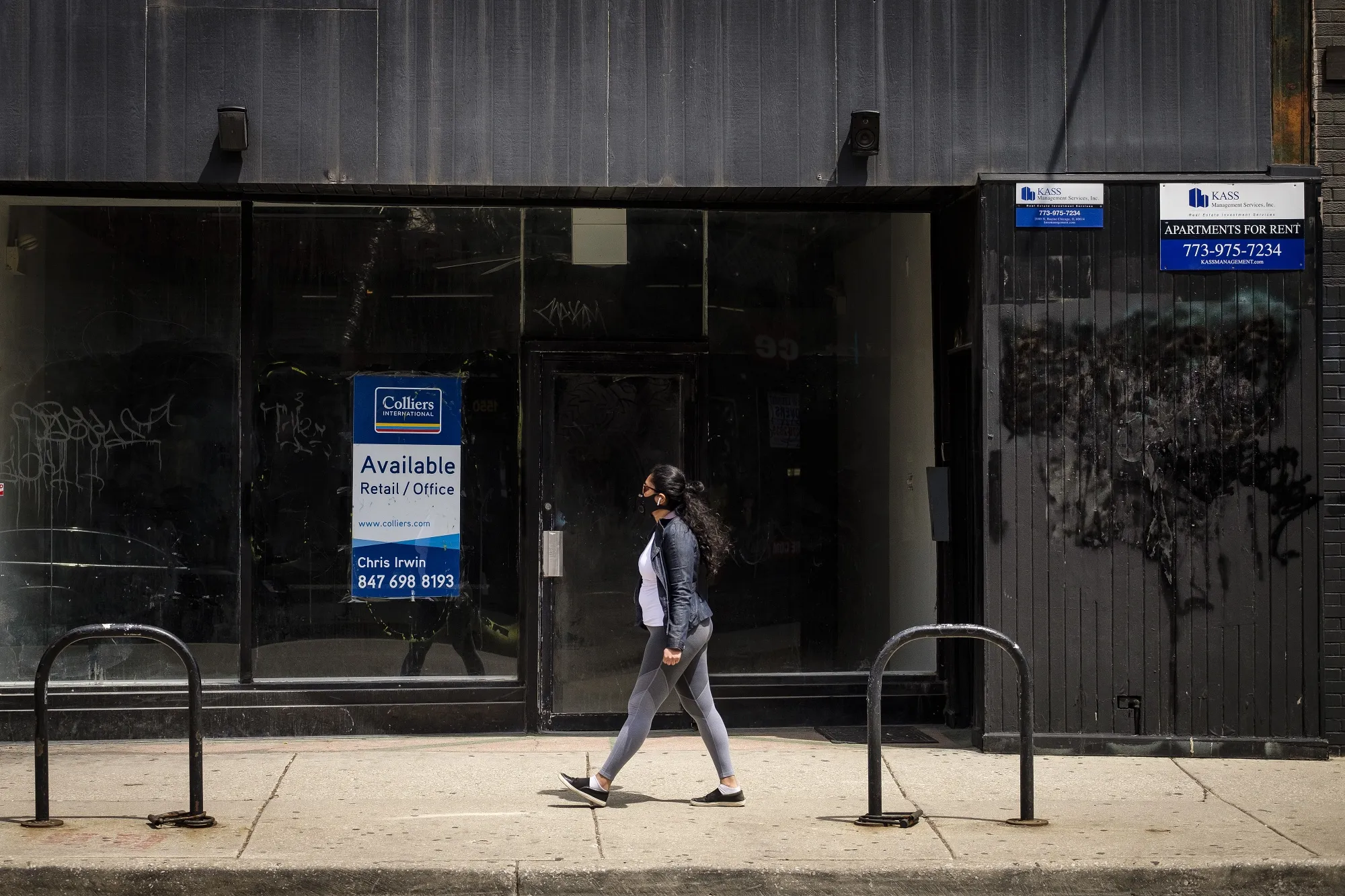 A pedestrian wearing a protective mask passes an empty retail space in Chicago on May 7, 2020.&nbsp;