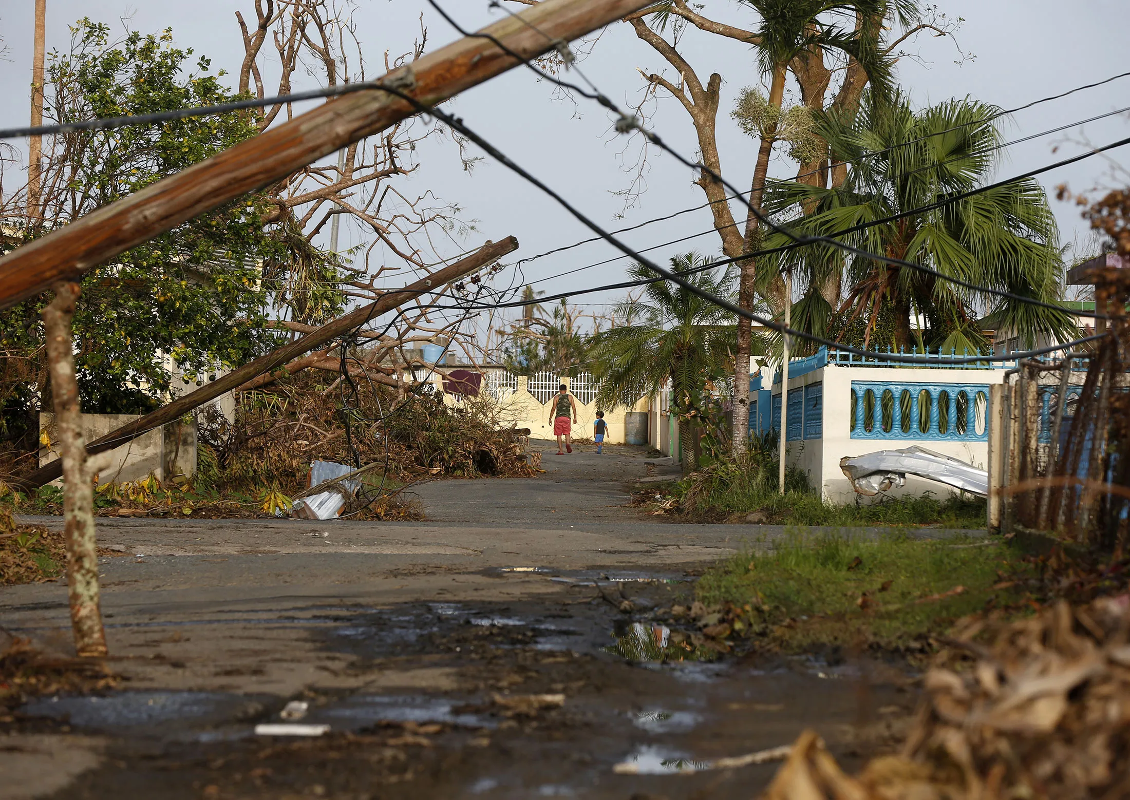 A man and child walk down street strewn with debris and downed power lines in the aftermath of Hurricane Maria, in Yabucoa, Puerto Rico, on&nbsp;Sept. 26, 2017.&nbsp;