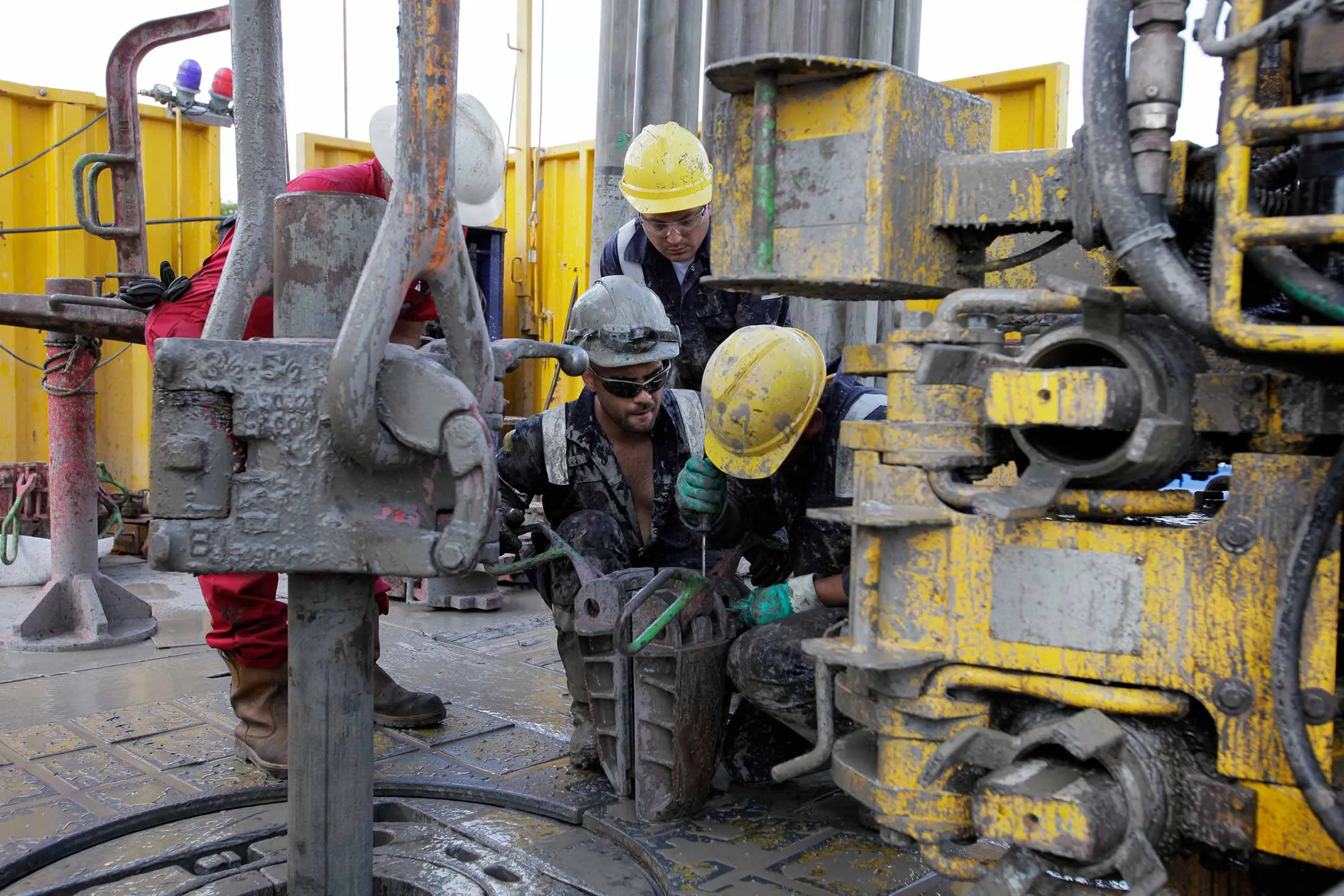 The muddied workers from Schlumberger Ltd., wearing a safety hard hat moves drilling pipes near to a rig at the geothermal energy drilling site in Villejuif, France.
