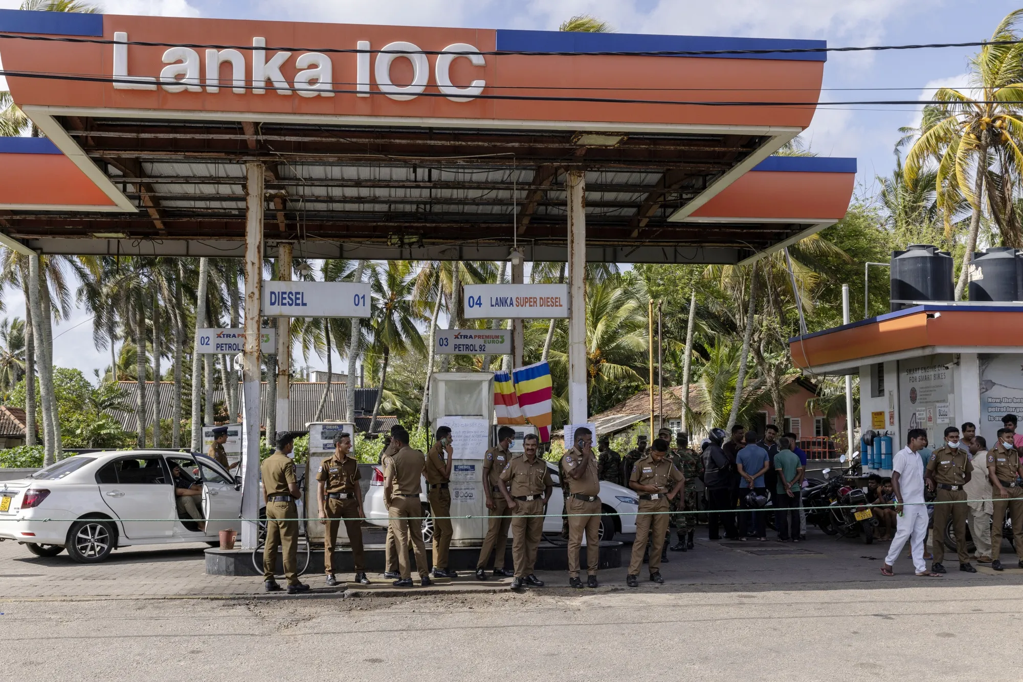 Police officers guard a gas station closed due to lack of supplies in Galle on June 28.