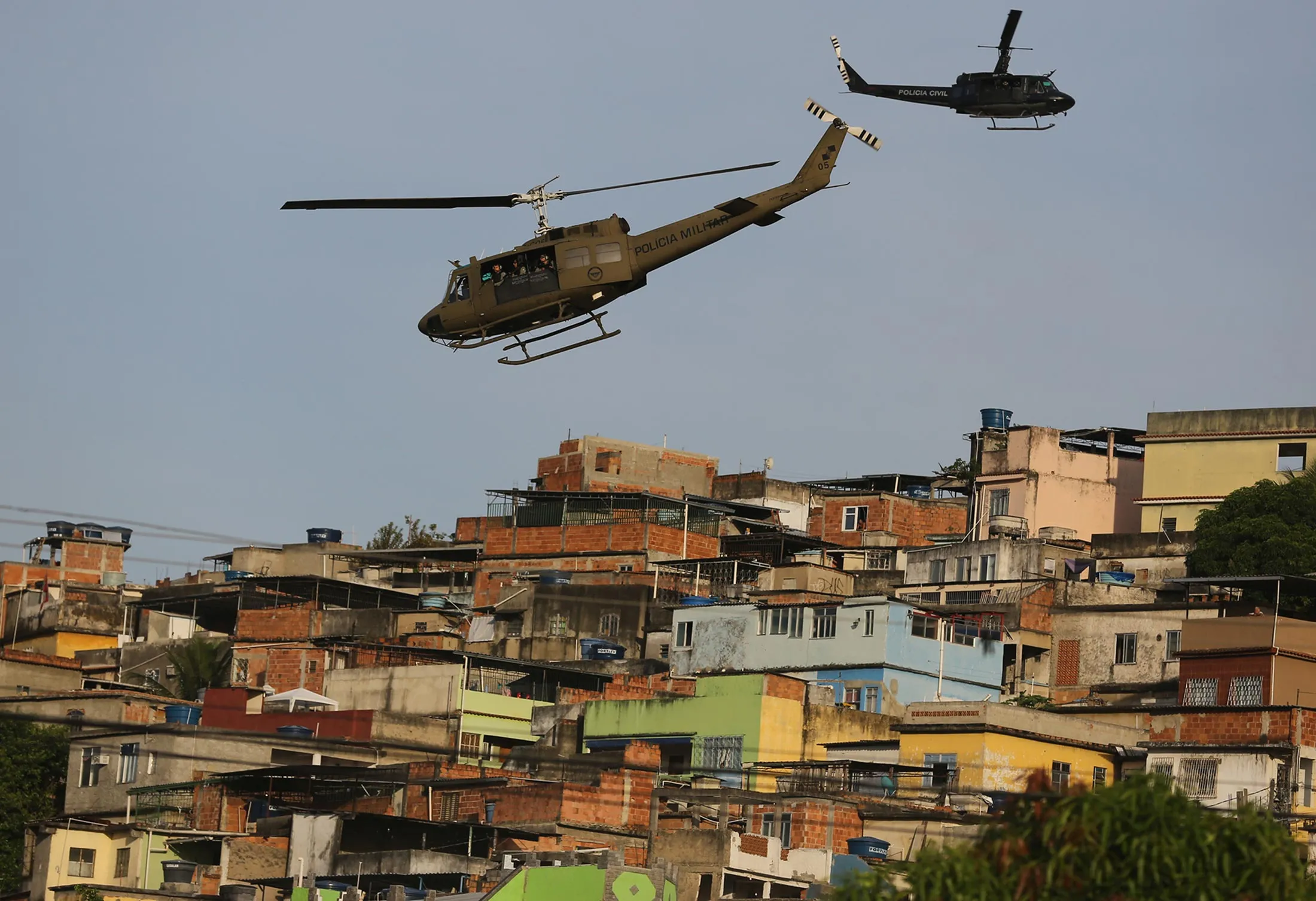 Police helicopters fly over the Mare slum complex during it's occupation in Rio de Janeiro, Brazil, Sunday, March 30, 2014.
