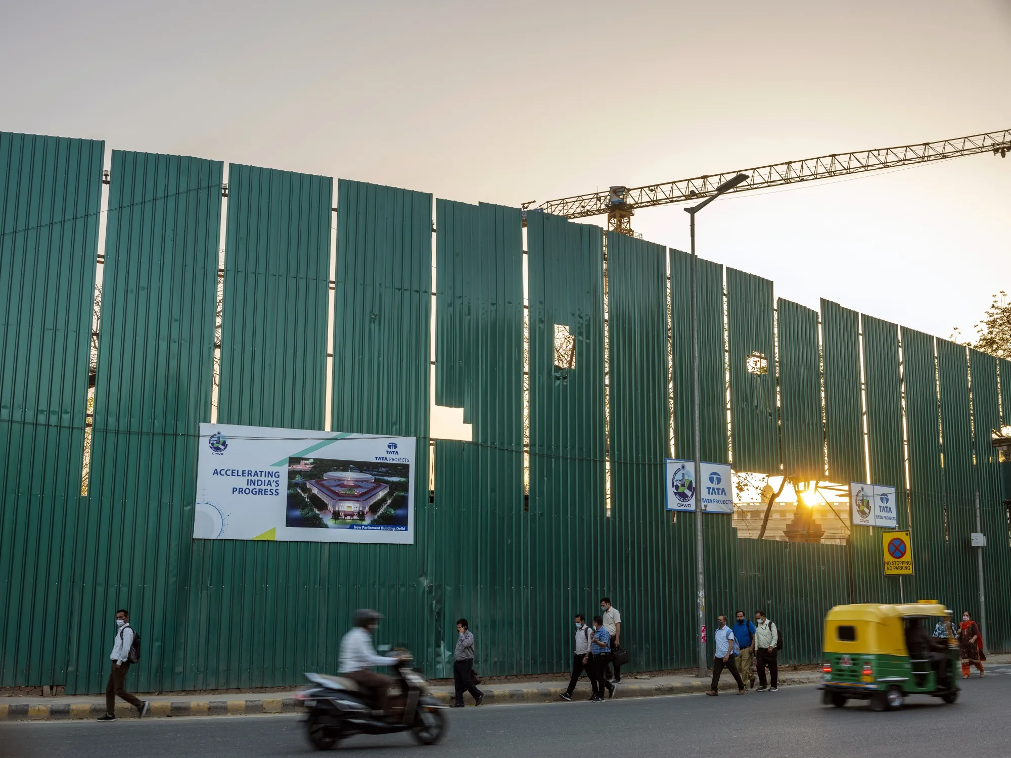 The sun setting over&nbsp;Parliament House is seen through a gap in construction hoardings&nbsp;that display an artist’s impression of the new parliament building,&nbsp;in New Delhi, on March. 26.