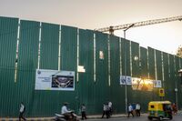 The sun setting over Parliament House is seen through a gap in construction hoardings that display an artist’s impression of the new parliament building, in New Delhi, on March. 26.