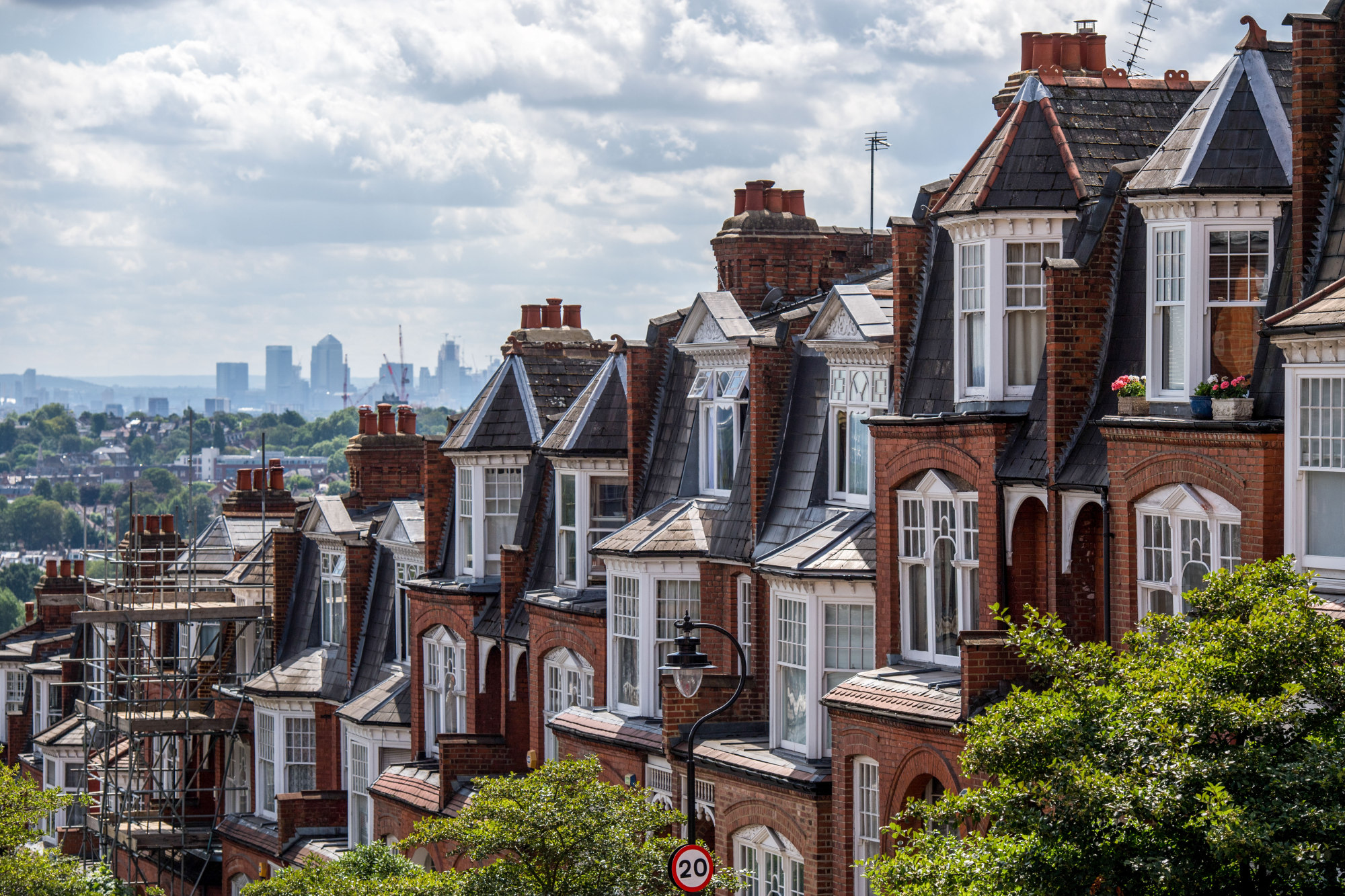 A terraced row of residential housing sit in the Muswell Hill district, in view of the Canary Wharf financial, business and shopping district of London, U.K., on Tuesday, July 31, 2018. U.K. house prices bucked their recent trend with a modest pick up in growth in July, according to Nationwide Building Society.