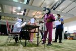 A frontline worker undergoes a temperature check at a registration counter at a vaccination center in Serdang, Selangor, Malaysia.