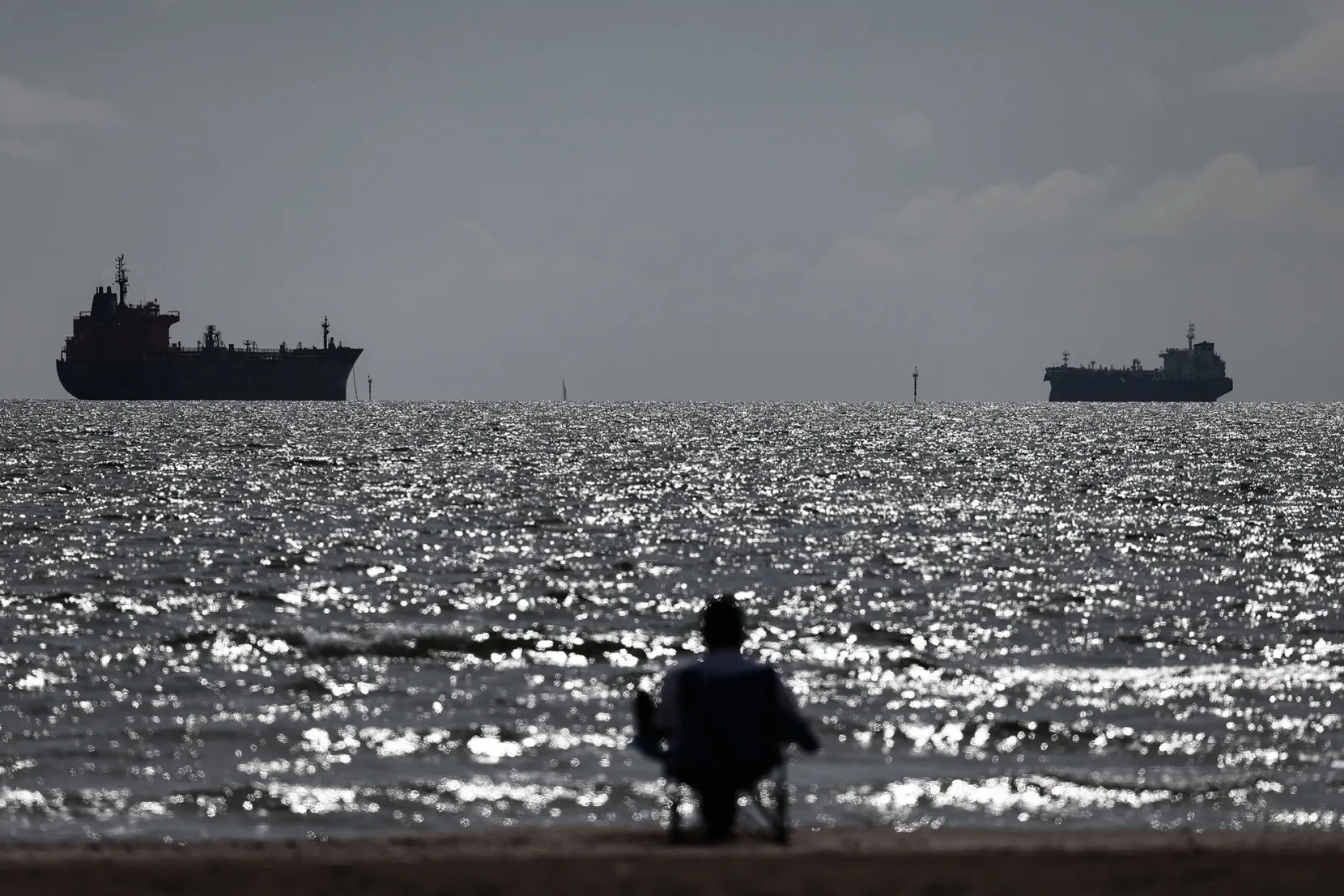 A person watches oil tankers.
