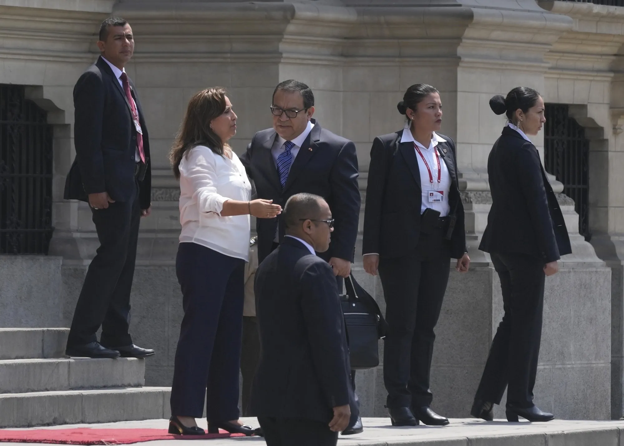 Surrounded by security, Peruvian President Dina Boluarte, second from left, and Prime Minister Alberto Otarola stand outside the government palace as Otarola departs in Lima, on Jan. 10.