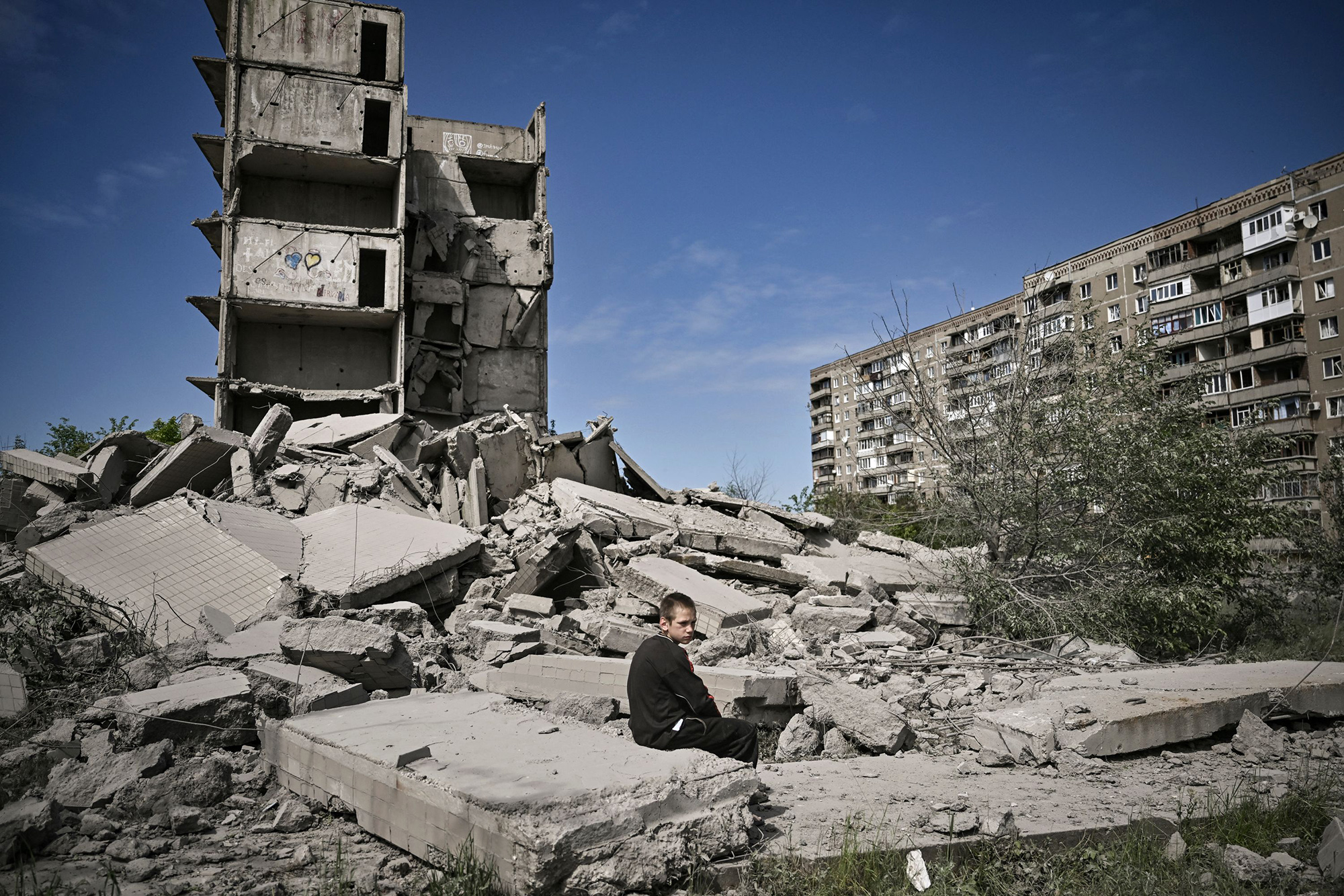A boy sits in front of a damaged building after a strike in Kramatorsk, in the eastern Ukrainian region of Donbas, on May 25.&nbsp;