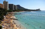 Tourists enjoy sunbathing, surfing, boating and swimming at Waikiki beach in Honolulu, Hawaii.