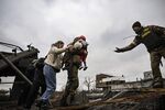 A Ukrainian serviceman carries a child while assisting people to cross a destroyed bridge as they evacuate the city of Irpin, northwest of Kyiv, on March 5.