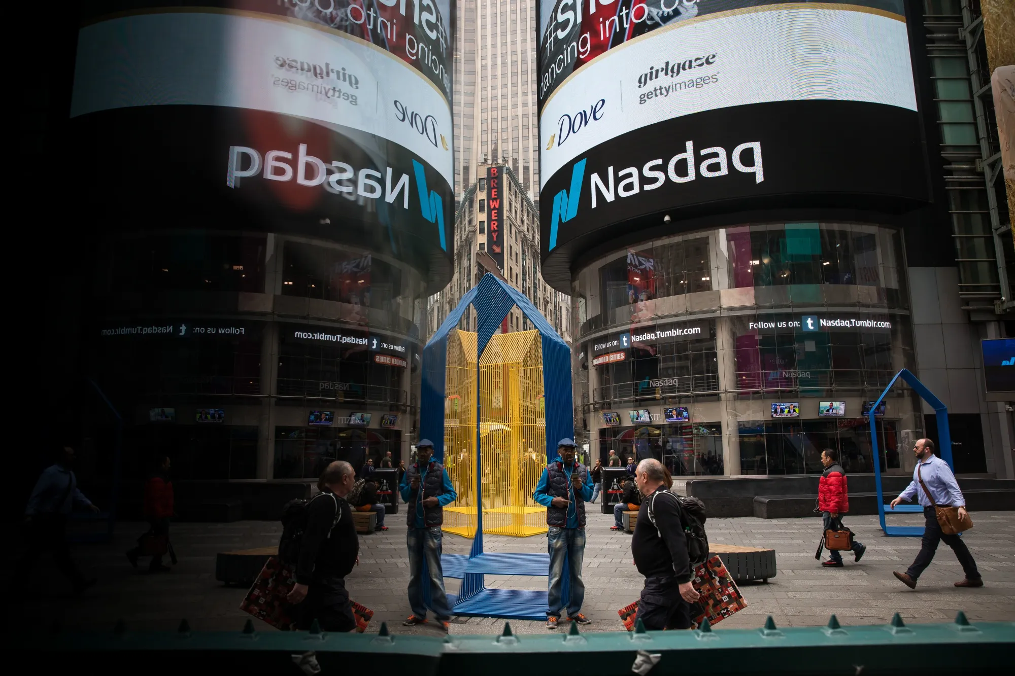 Pedestrians pass in front of the Nasdaq MarketSite in the Times Square neighborhood of New York.