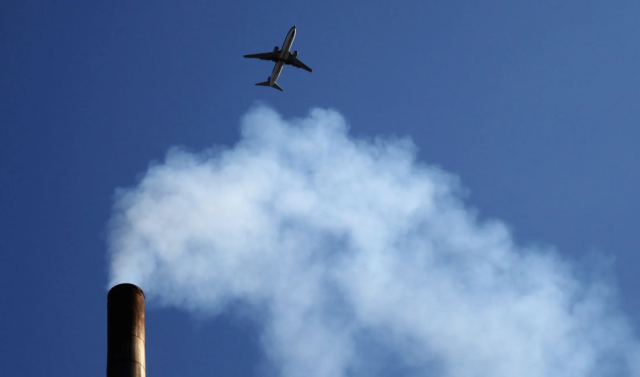 A plane flies over a chimney on May 30, 2012, in Beijing.

