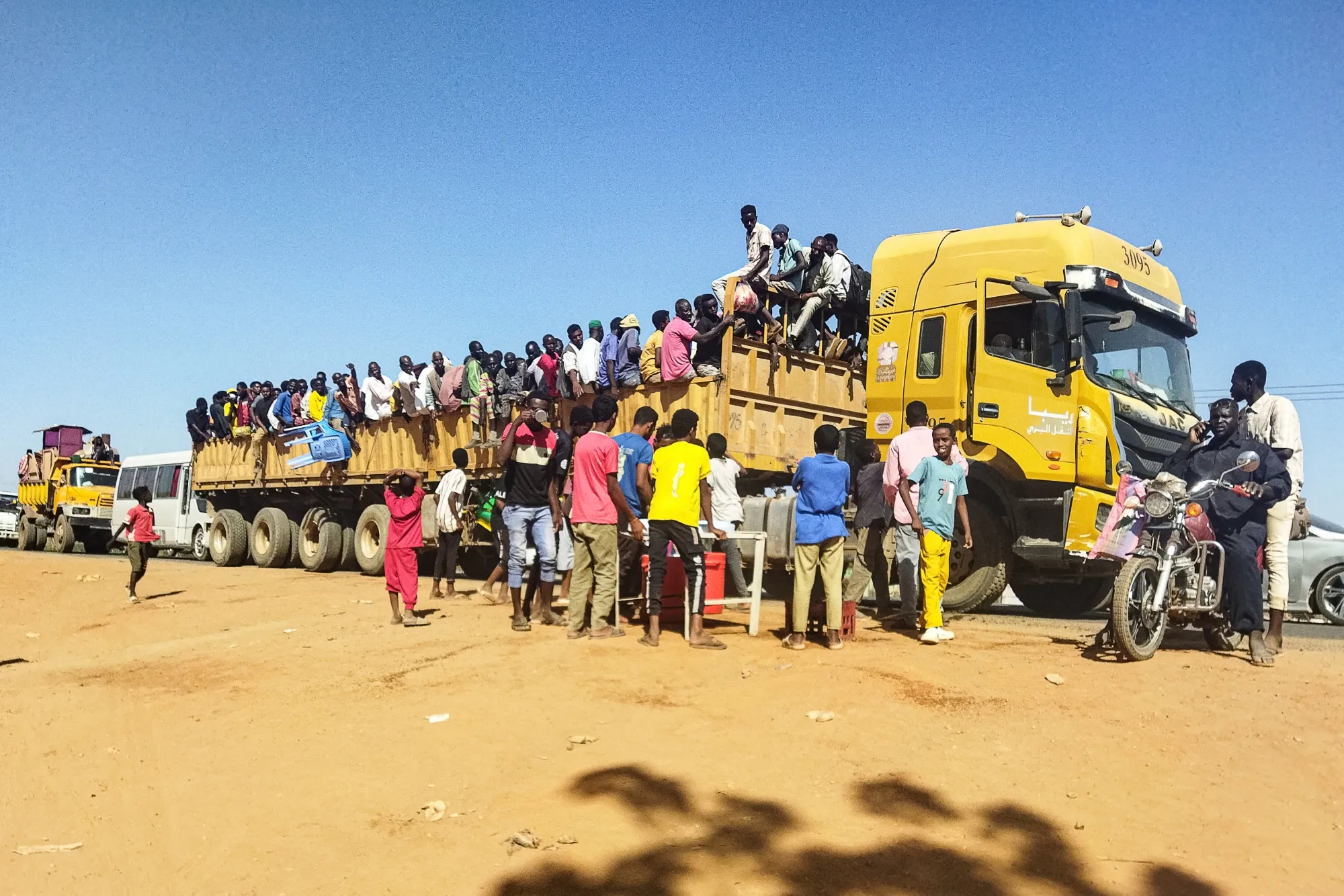 People try to get on top of the back of a truck moving along a road in Wad Madani, on Dec.&nbsp;16.&nbsp;