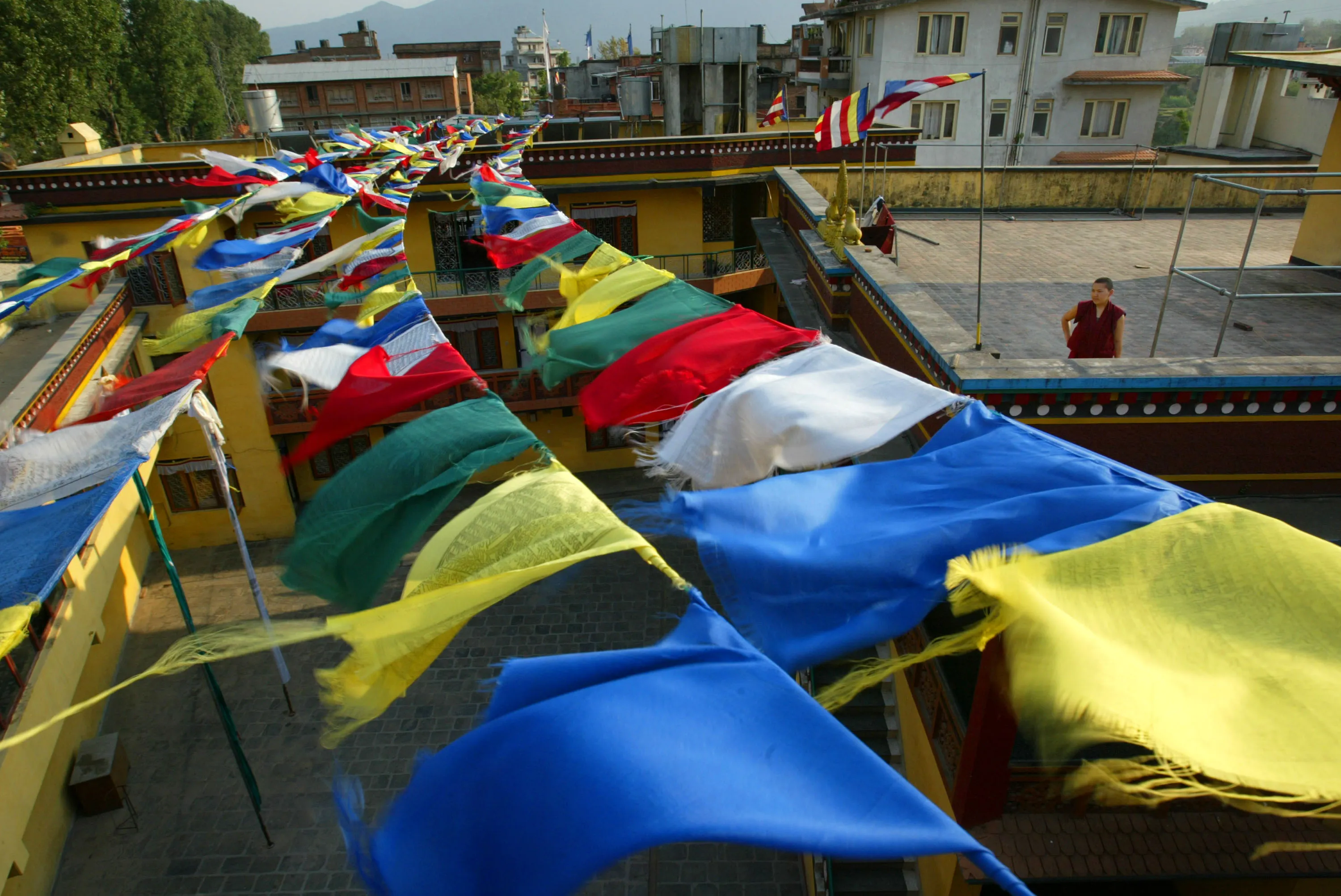 KATHMANDU, NEPAL - MAY 19:  Tibetan prayer flags blow in the wind from the rooftop of the Keydong Thuk-Che Choling Monastery on May 19, 2003 in Kathmandu, Nepal.  88 nuns live in the nunnery school in a Tibetan neighborhood of the city.  Buddhist nuns face the same discrimination that affects all women in Nepal.  Out of all the Buddhist nuns in Nepal, only a small fraction are able to live in nunneries, where they may receive limited education in learning english and reading and reciting Tibetan scriptures.  They are often the only females from their villages with any education at all since Nepal has a severely low female literacy rate.  Many Buddhist monks and nuns perished in the turbulent years following the 1959 Chinese takeover of Tibet.  (Photo by Paula Bronstein/Getty Images)