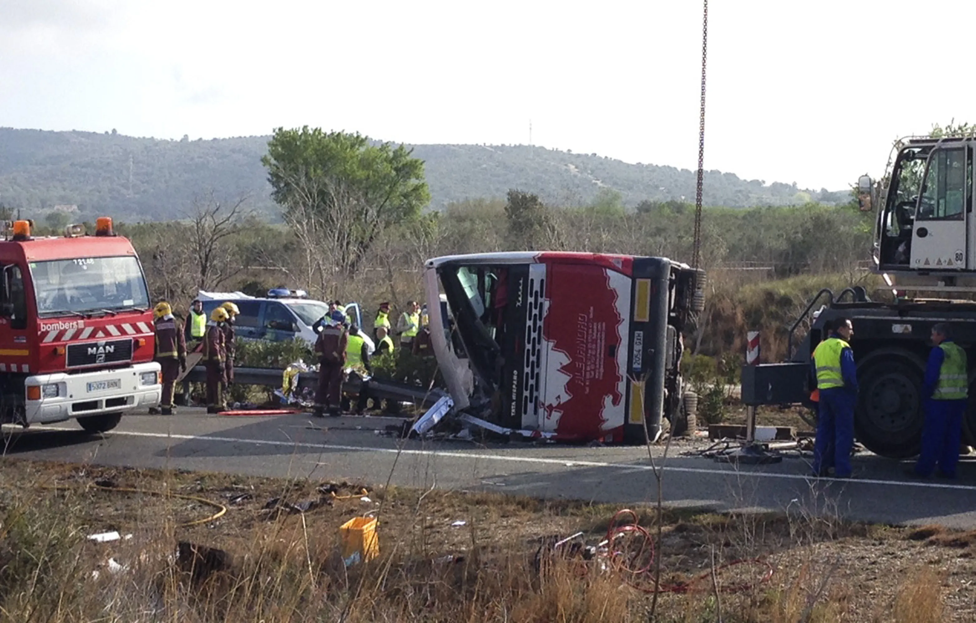 Emergency services personnel stand at the scene of a bus accident crashed on the AP7 highway that links Spain with France along the Mediterranean coast near Freginals halfway between Valencia and Barcelona early Sunday, March 20, 2016. AP Photo
