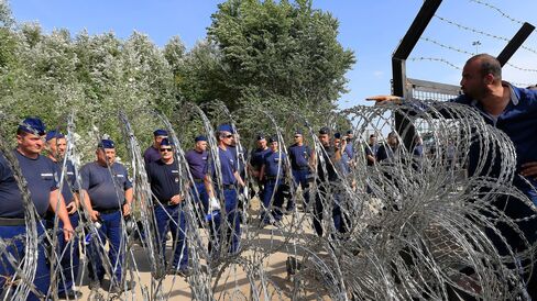Hungarian security forces stand guard as refugees continue waiting on the Serbian - Hungarian border in Horgos, Serbia after Hungarian authorities closed its borders on September 16, 2015.