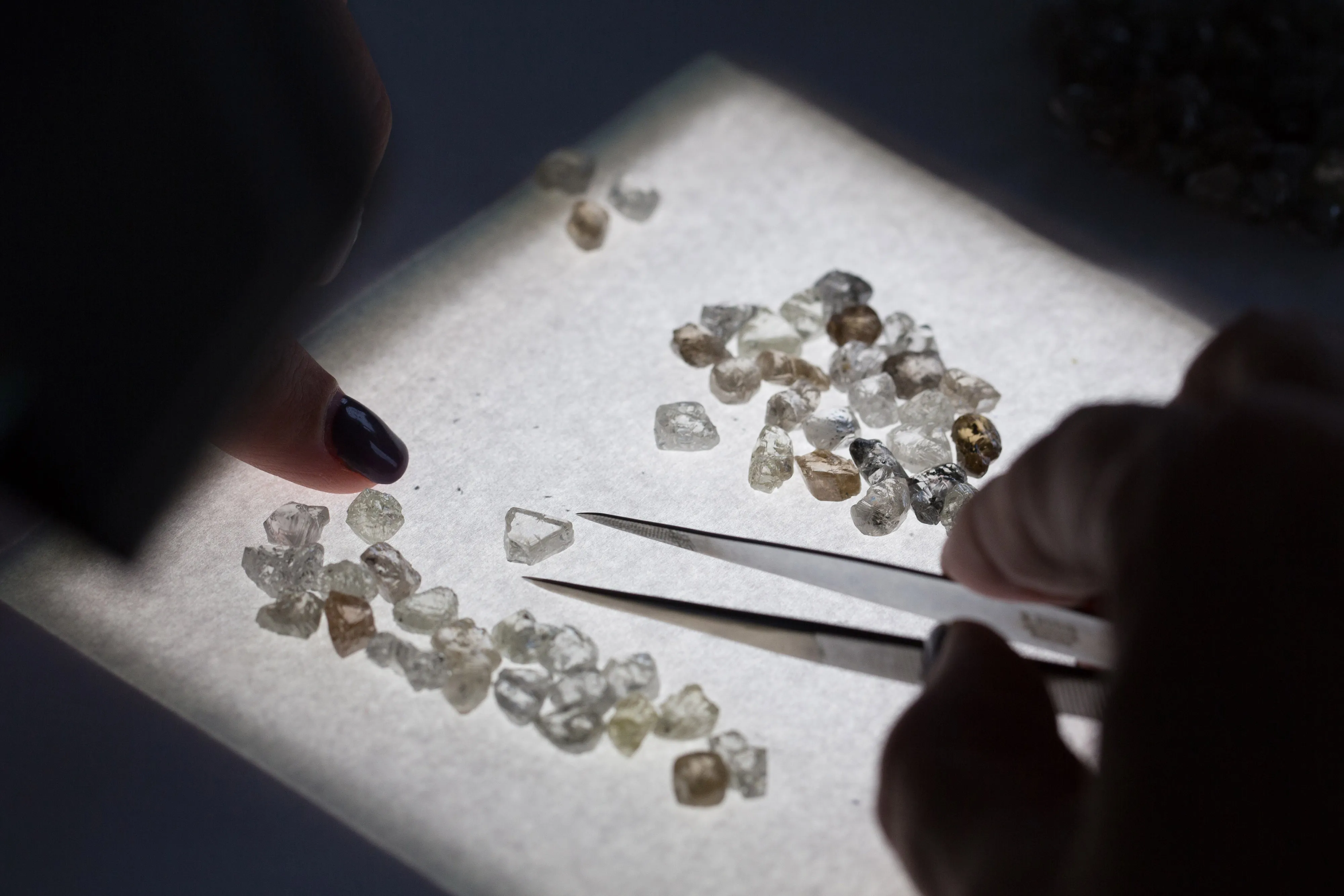 An worker sorts through a collection of rough diamonds at a&nbsp;sorting center in Moscow, Russia