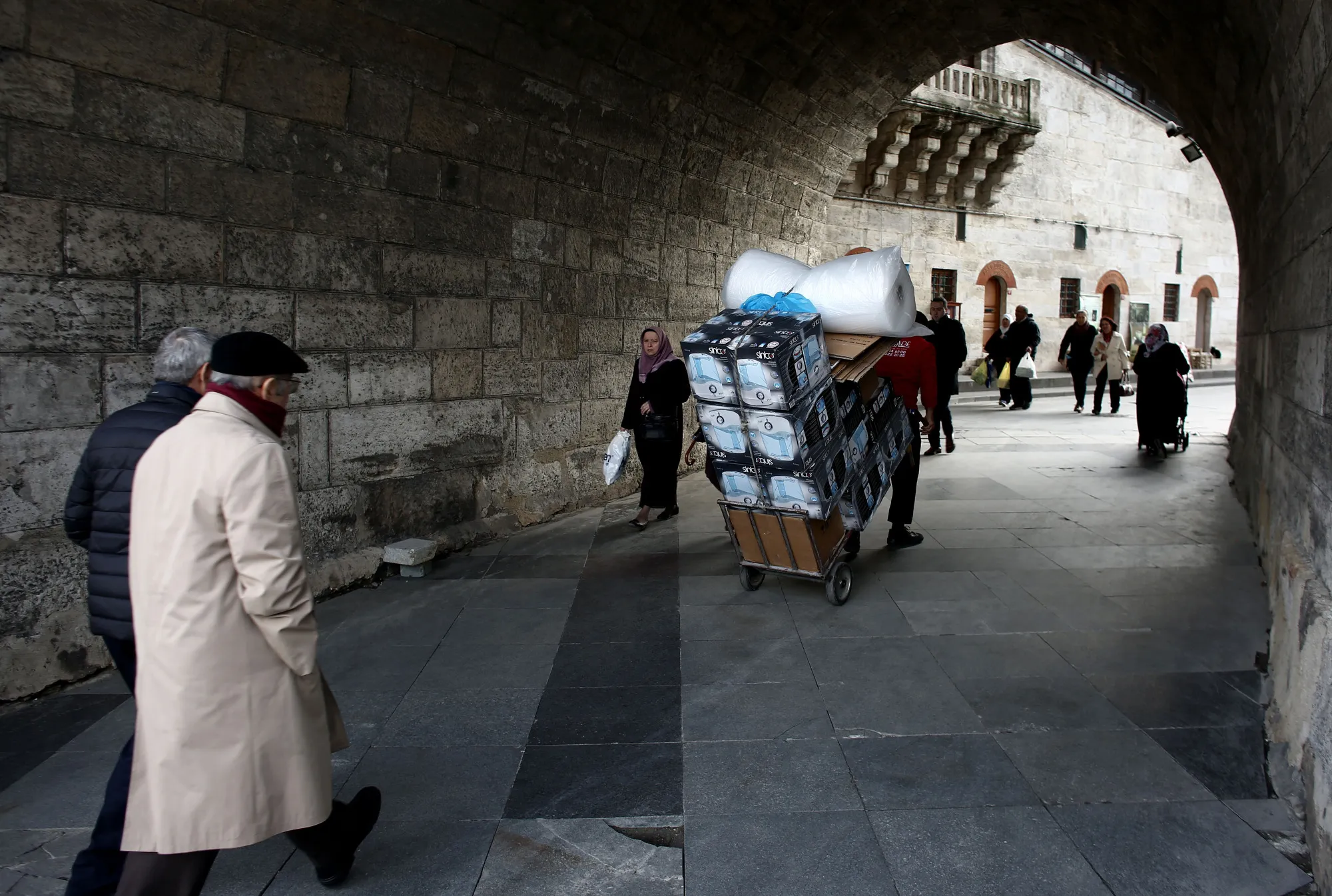 A worker wheels a cart laden with goods through an ancient passageway in Istanbul.