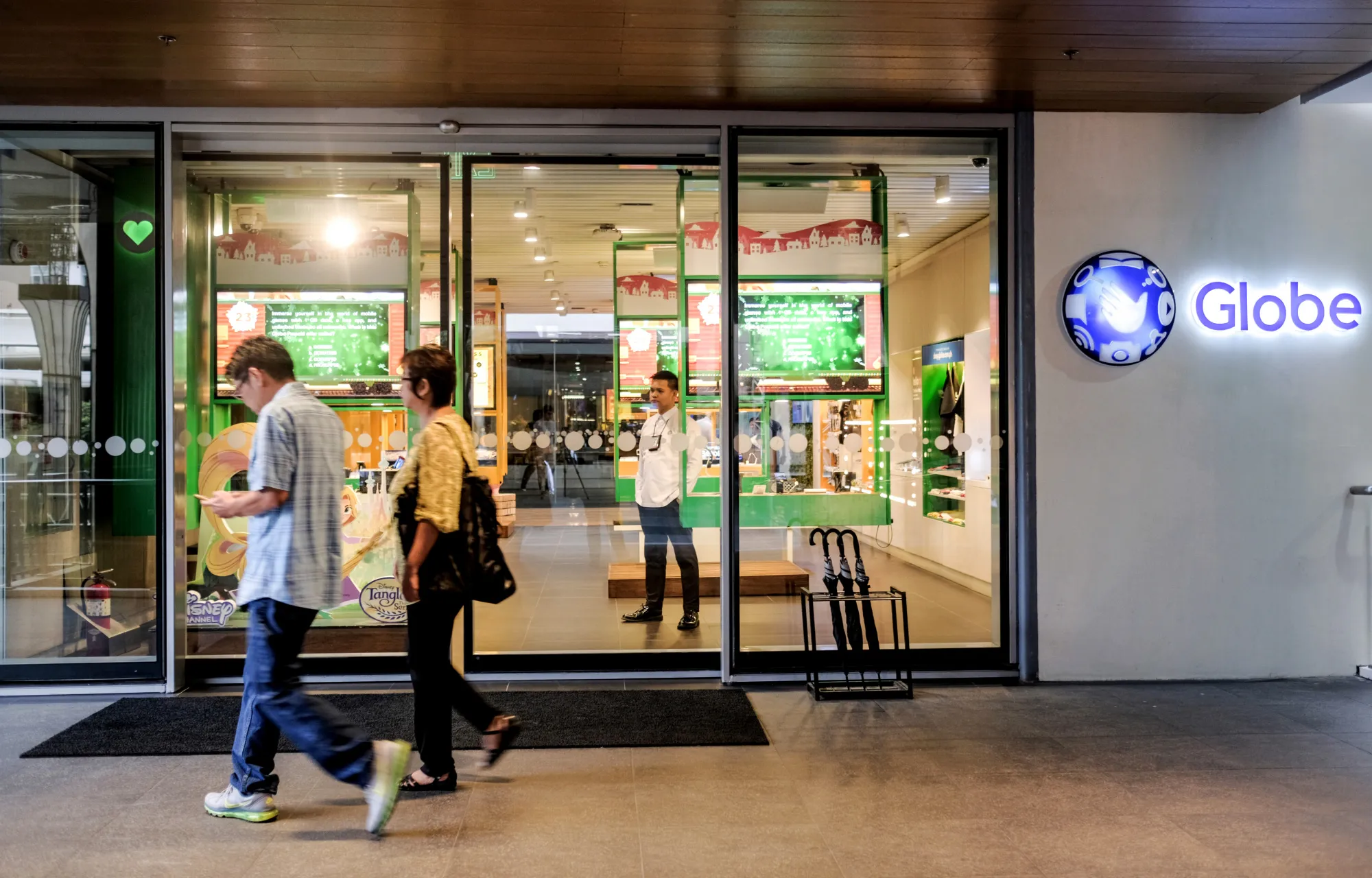 Pedestrians walk past a Globe Telecom Inc. Iconic store in Manila, the Philippines.
