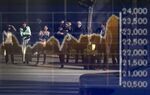 Pedestrians are reflected in an electronic stock board outside a securities firm.