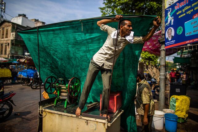 A roadside vendor is seen setting up shade to escape from suns heat in Bhadra market in Ahemdabad, Gujarat, India, on Friday, May 6, 2023. Photographer: Prashanth Vishwanathan/Bloomberg