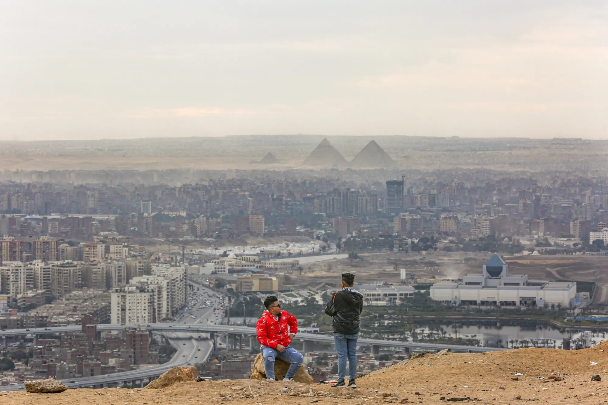 Visitors look out towards the Giza pyramid complex, viewed from Al Mokattam mountain, in Cairo, Egypt.