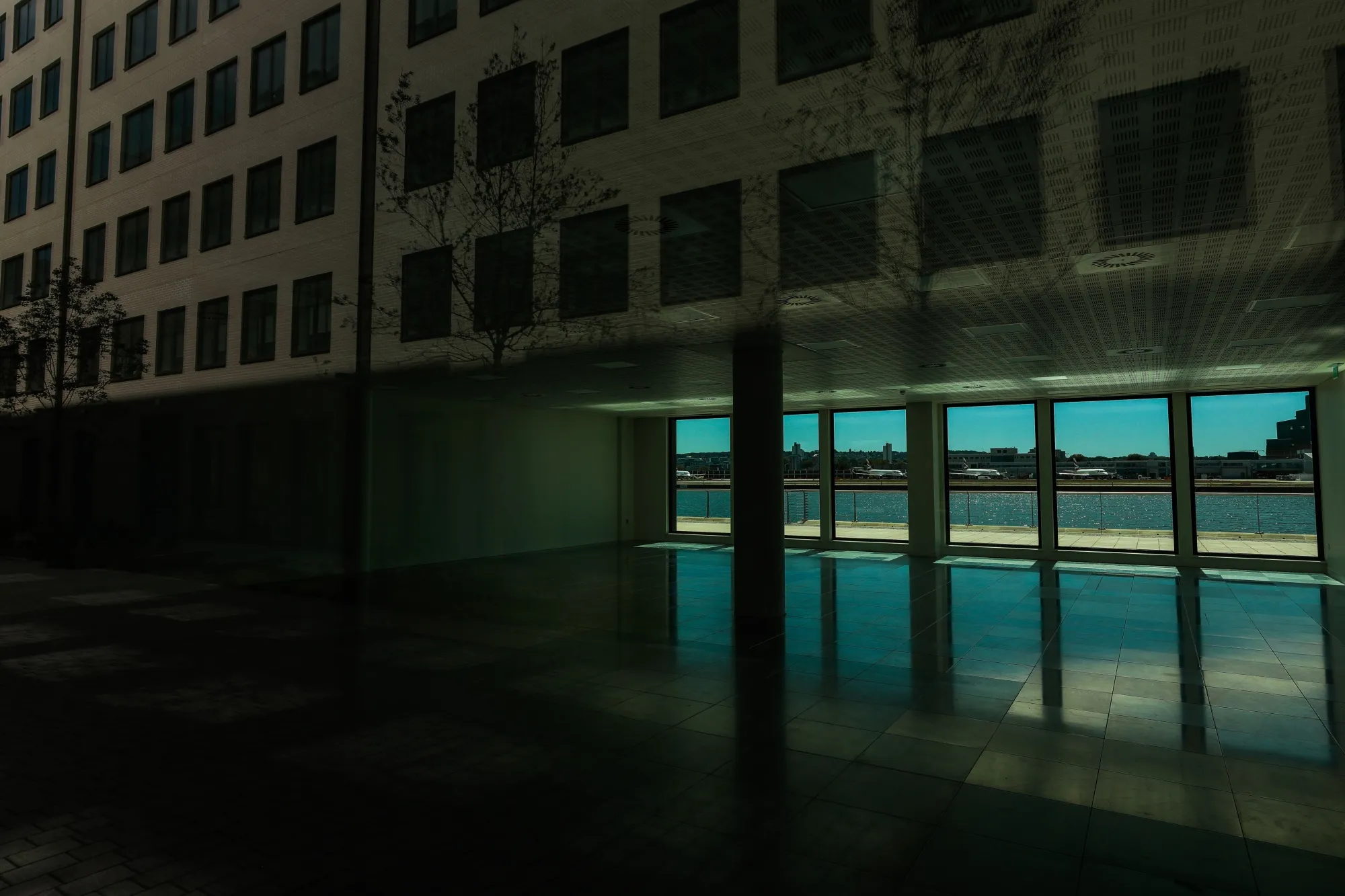 Aircraft sit parked at City Airport in this view through an empty space in a building at the Royal Albert Docks development in London, July 30.