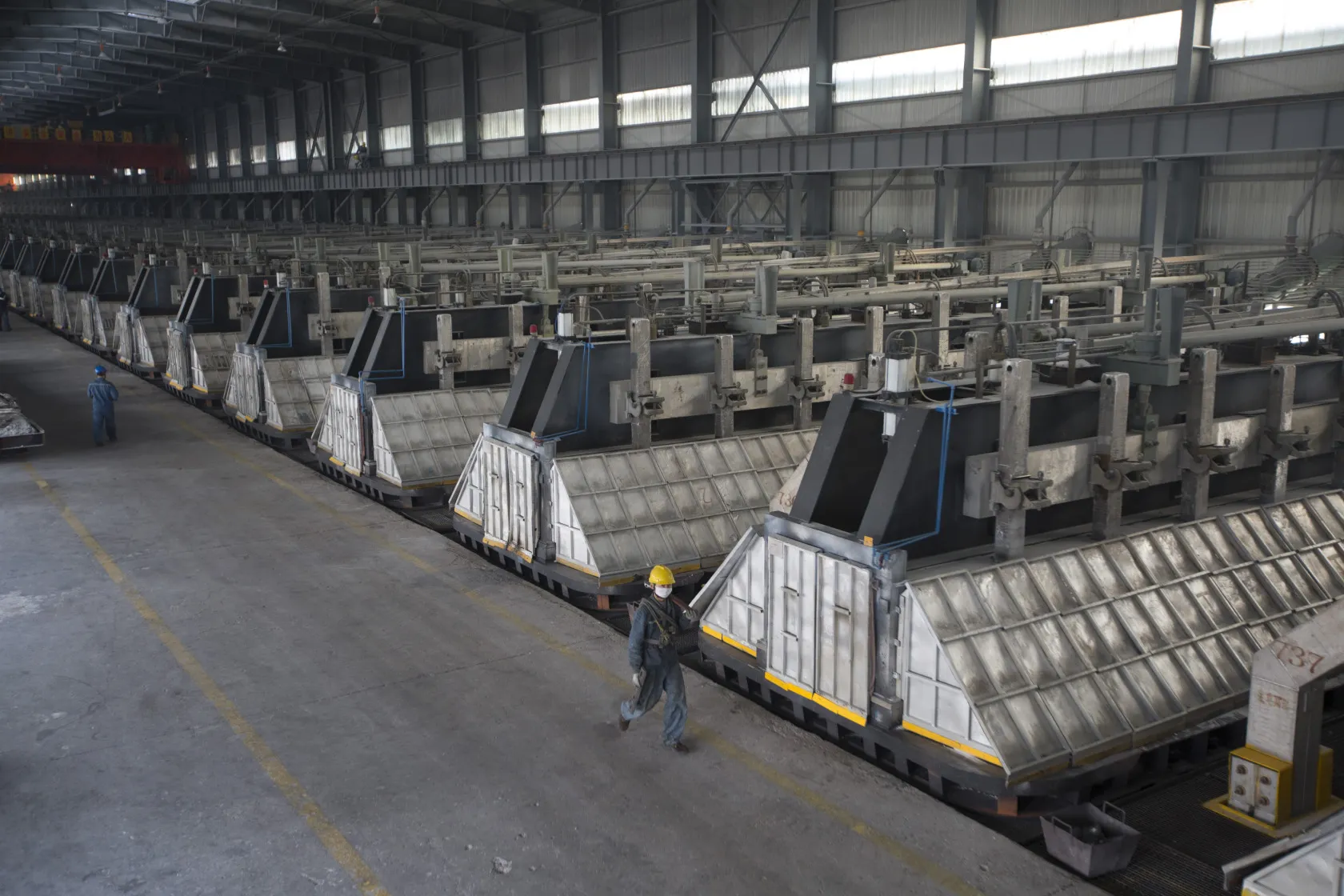 Employees walk through the aluminum smelting room at the China Hongqiao Group Ltd. aluminum smelting facility in Zouping, China, on Monday, Nov. 4, 2013. China Hongqiao Group is China's largest private aluminum maker.