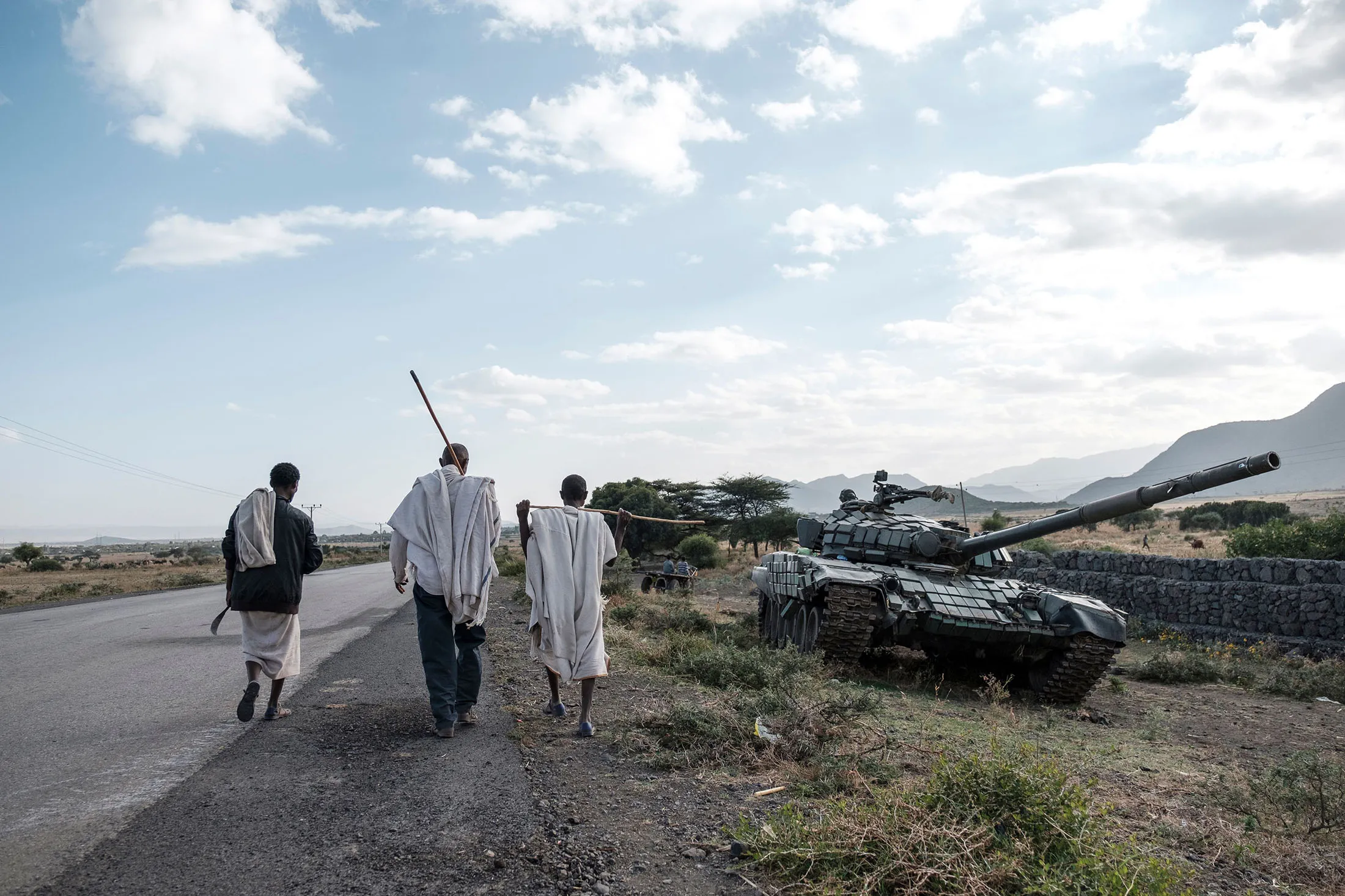 People walk next to an abandoned tank belonging to Tigrayan forces near Mehoni, Ethiopia.