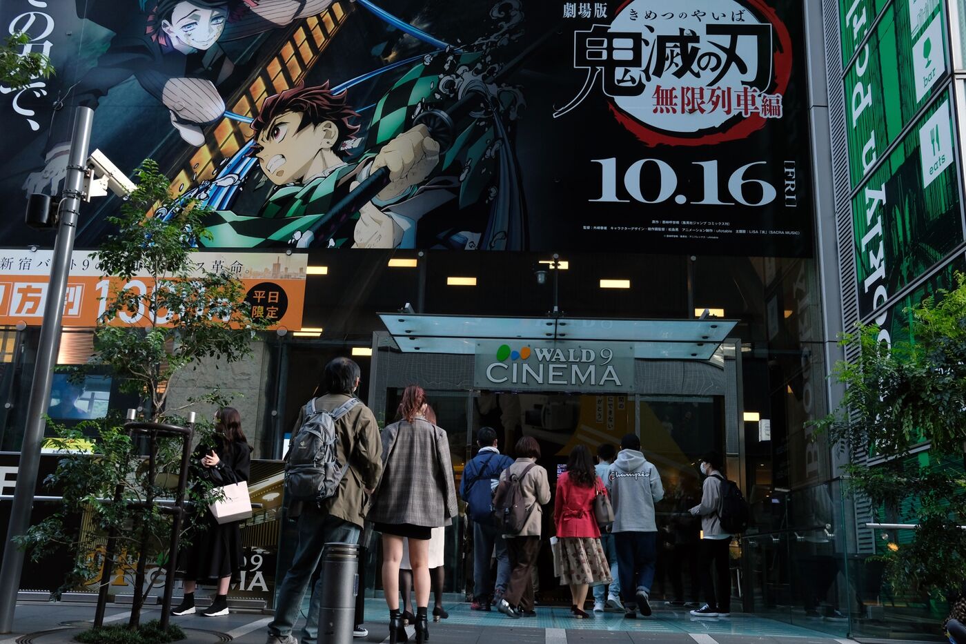 Movie goers line up under an advertisement of a film 'Demon Slayer: Kimetsu no Yaiba' outside a movie theater in the Shinjuku District of Tokyo, Japan,