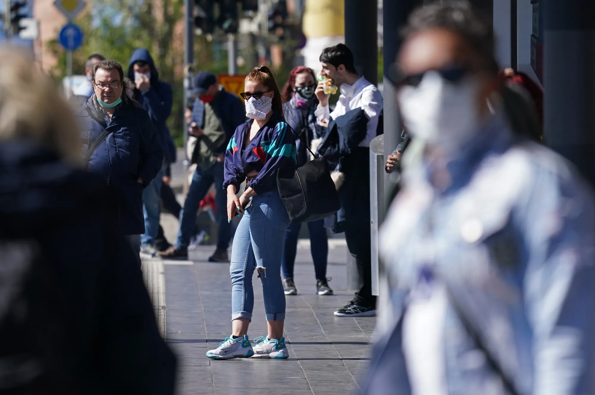 People wearing protective face masks wait for a street tram in Leipzig, Germany.