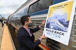 An aide to then-presidential candidate Joe Biden affixes a poster to an Amtrak train during a campaign stop in Alliance, Ohio, on September.&nbsp;