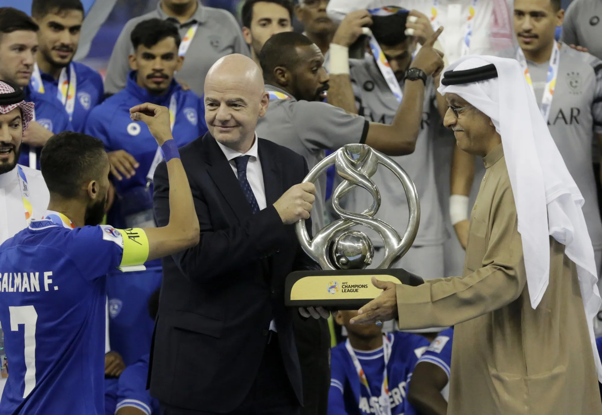 FIFA President Gianni Infantino, center, prepares to present the trophy to Saudi Arabia's Al Hilal midfielder Salman Al-Faraj, left, after winning the AFC Champions League final soccer match against South Korea's Pohang Steelers 2-0, at the King Fahd International Stadium in Riyadh, Saudi Arabia, Tuesday, Nov. 23, 2021. (AP Photo/Amr Nabil)